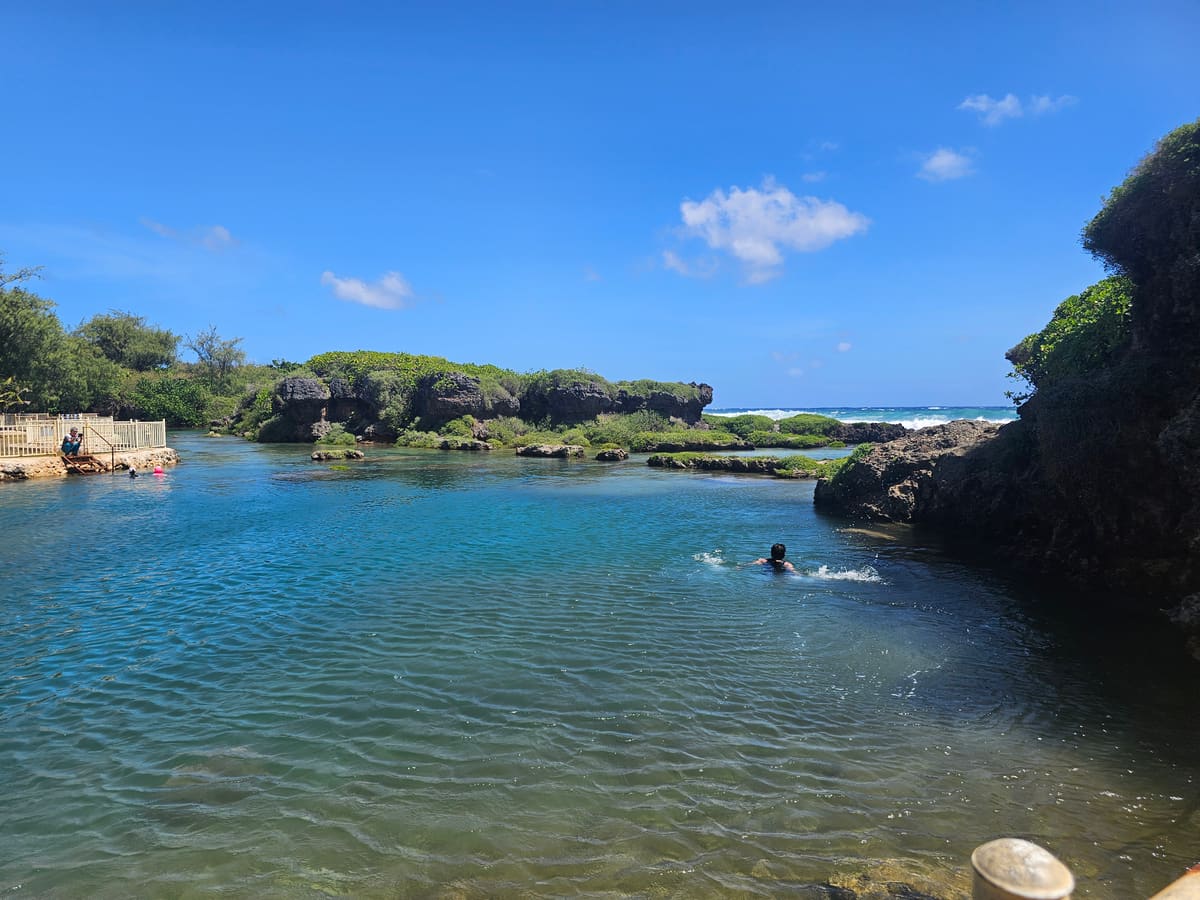 イナラハン天然プールで泳ぐ人と海側の岩場